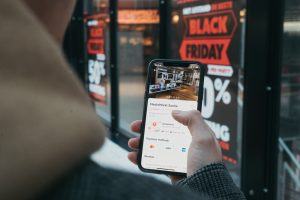 consumido mira ofertas de Black Friday en su móvil frente un escaparte
