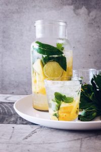 Jarra y vaso de agua con limón y menta