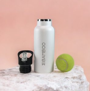 Botella térmica polar con tapón deportivo y una botella de tenis sobre una roca